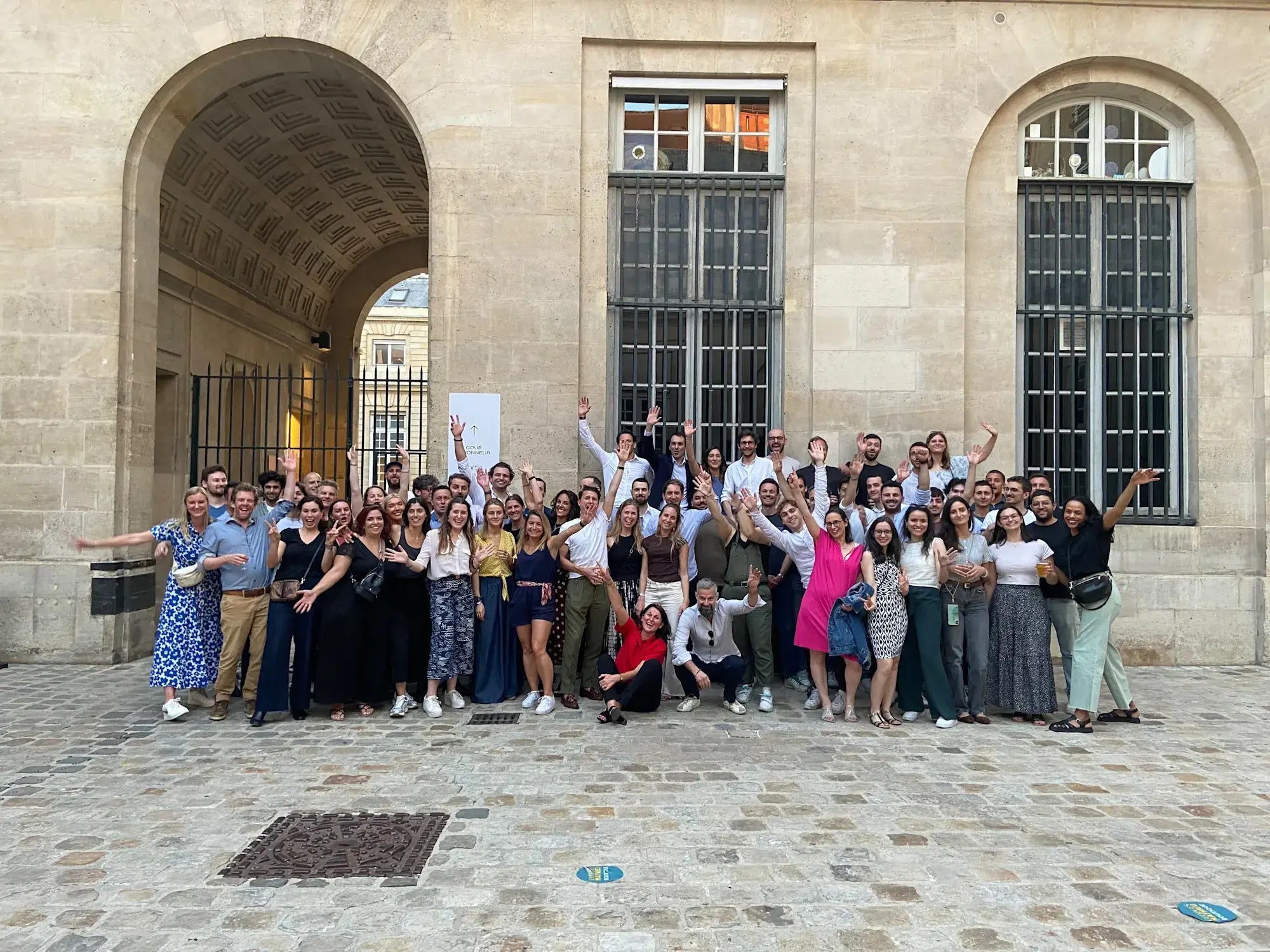 YOOBIC teammates posing for a group photo in the stone courtyard of a Paris venue, some holding drinks