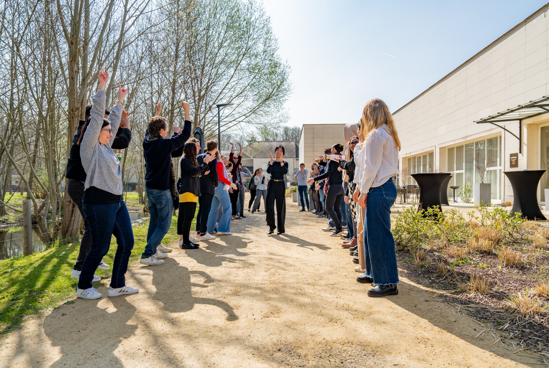 YOOBIC teammates forming a cheering corridor outdoors beside a canal at the March 2025 boot camp